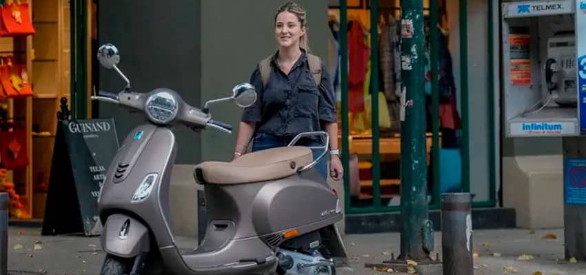 Muestra en recorrido urbano de motos automaticas para mujer estacionada con mujer alegre gracias a su elección de moto