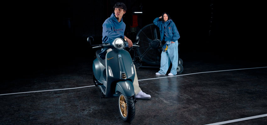 Mujer y hombre con chaqueta brandeada de Vespa Colombia esperando para asesorar adecuadamente sobre motos italianas en Colombia